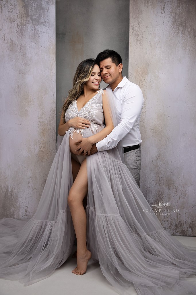 mom and dad pose together for a series of maternity portraits in grey celebrating their soon to be baby boy