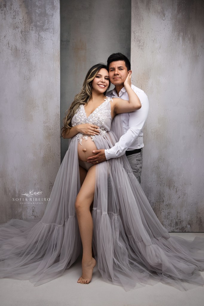 mom and dad pose together for a series of maternity portraits in grey celebrating their soon to be baby boy