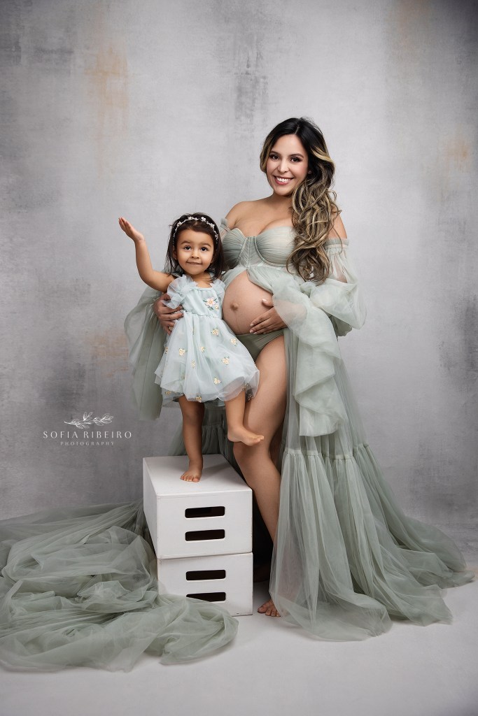 mom laughs as her baby girl strikes a funny pose during her maternity portrait session in glen ridge nj
