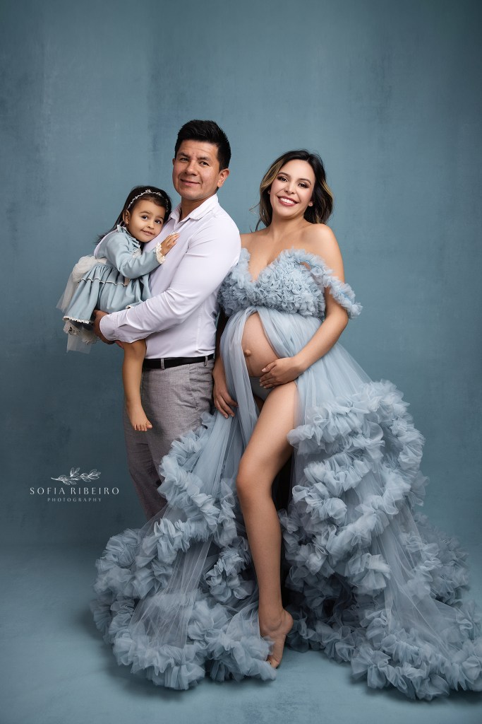 a growing family of three take a sweet portrait celebrating their soon to be fourth family member in shades of blue