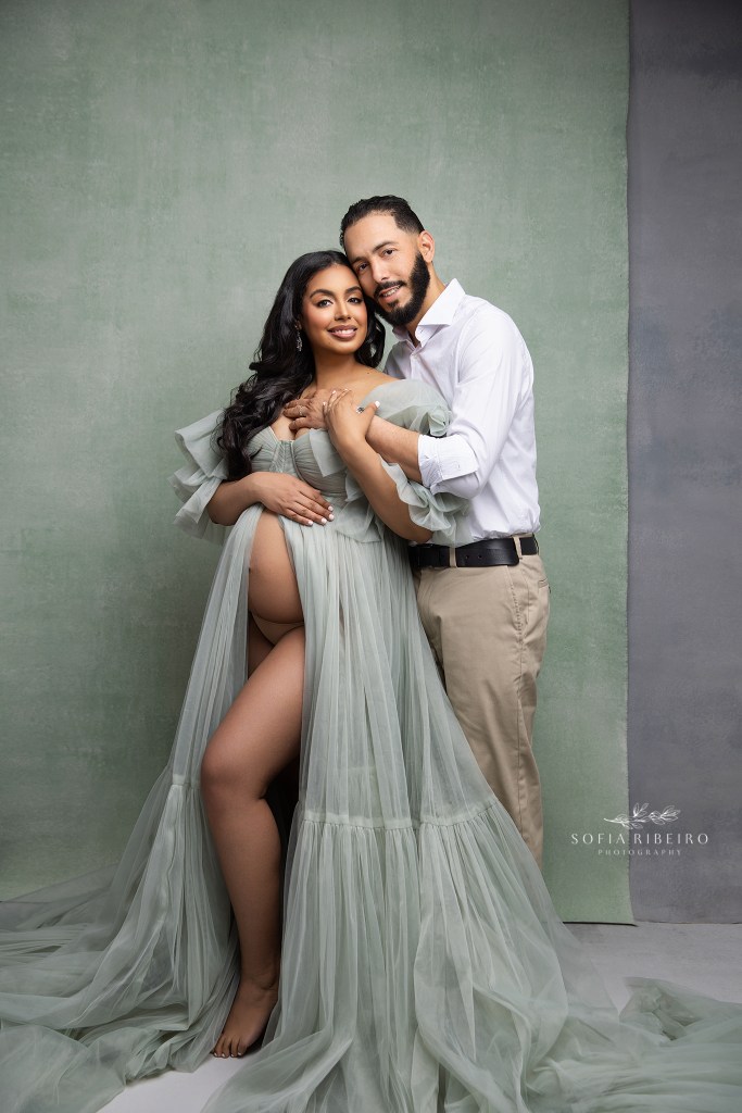 passaic nj maternity photographer captures an expecting couple's portrait together against a sage green backdrop