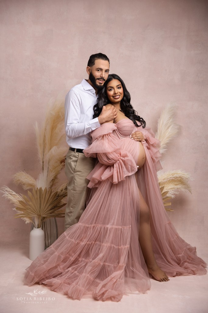 mom and dad pay homage to their soon to arrive baby girl in a sweet pink set with at a passaic nj maternity photographer's studio