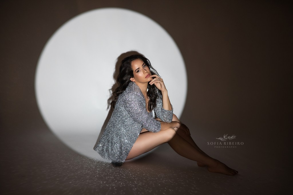 a spotlight highlights a chic pose and outfit in silver sequins for a birthday portrait session