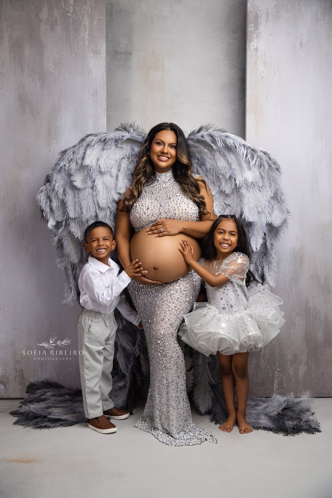 mom and her two older children pose together snuggling her baby bump for a beautiful portrait