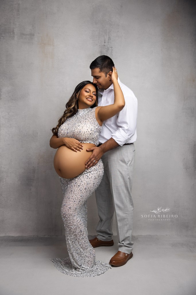 mom and dad share a sweet moment in matching silver and grey tones for maternity photos
