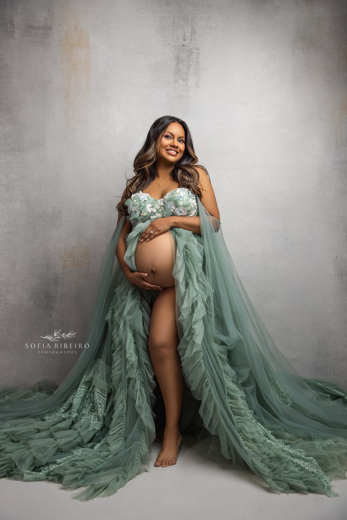 mom cradles her baby bump for a glowing, happy portrait in studio