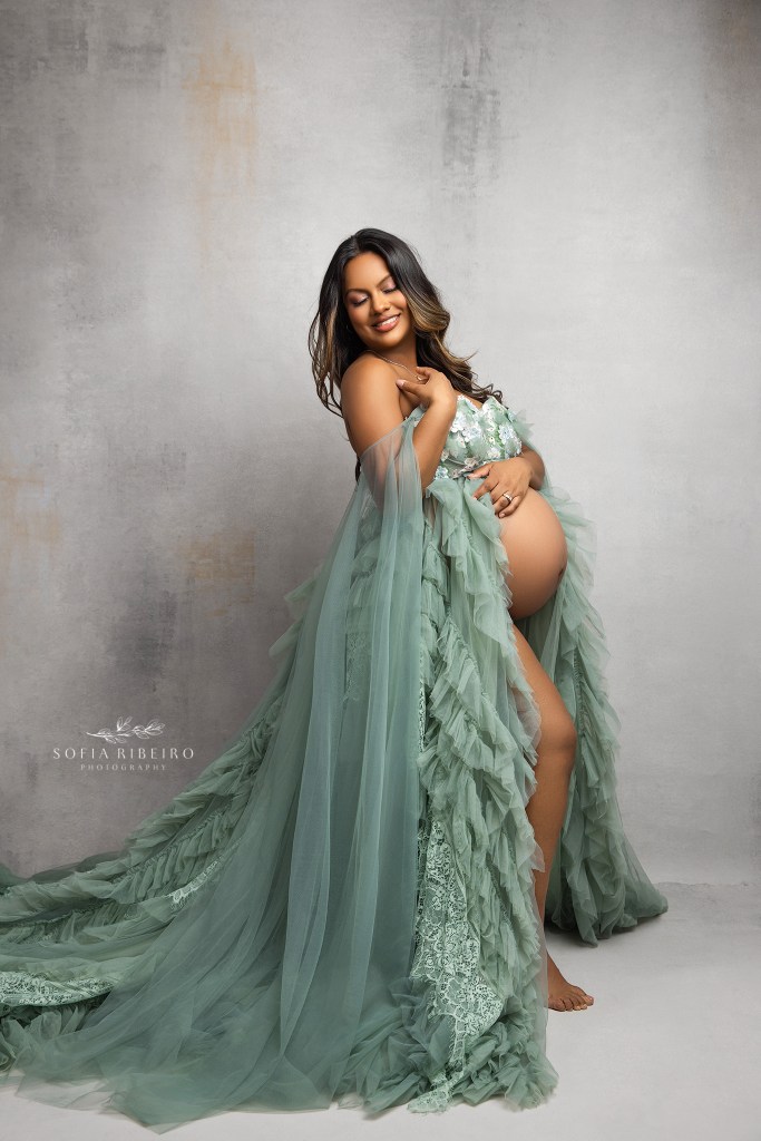 a mom to be ins radiant and smiling in a tender moment captured on camera during a maternity photo session