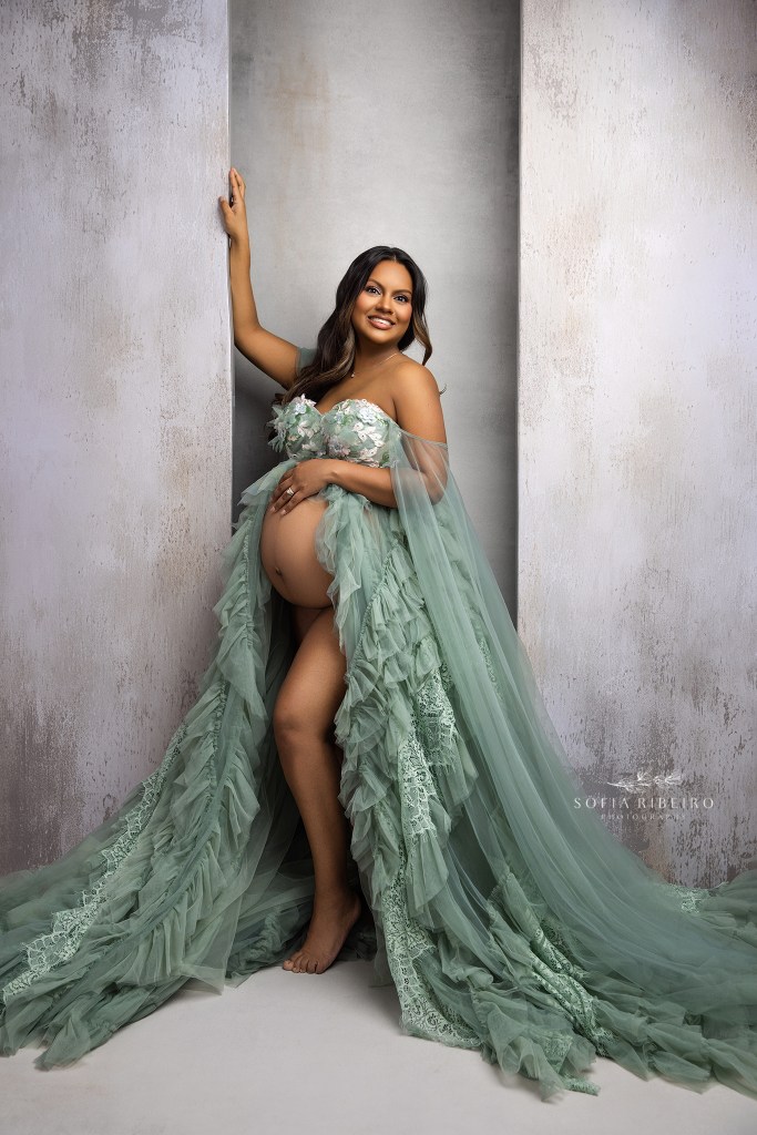 an expectant mom is radiant in sage green against a grey backdrop for maternity photos in franklin lakes nj