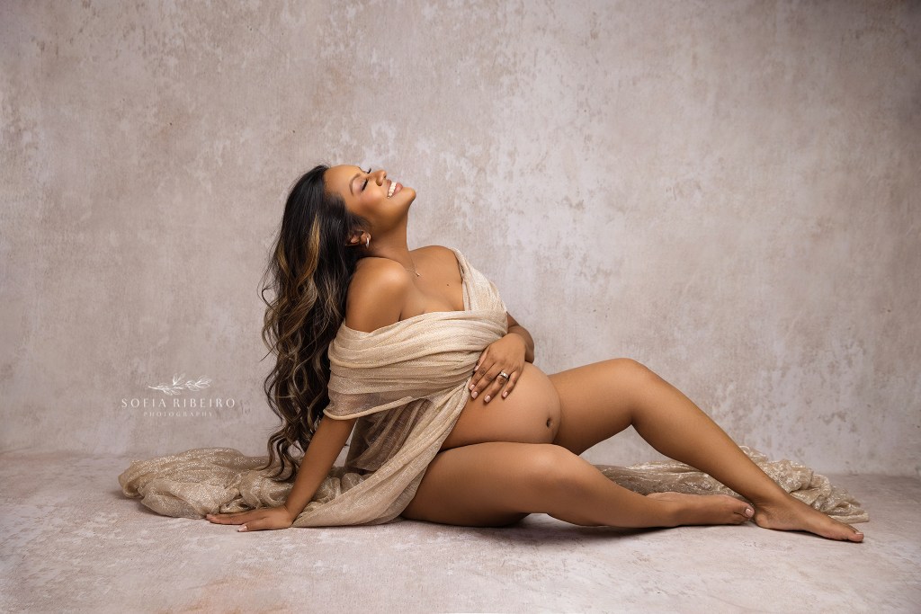franklin lakes nj maternity photographer captures a sexy pose for a mom to be, smiling and draped in gold