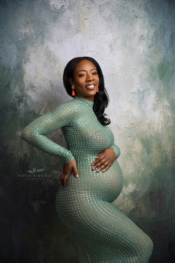 franklin nj maternity photographer captures a radiant mom to be in a figure hugging green gemstone dress against a painted backdrop