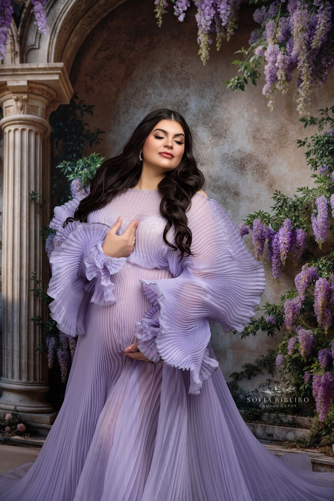 mom cradles her belly lovingly in a purple pleated dress