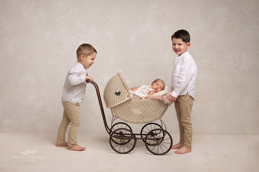 maplewood nj newborn photographer captures two older siblings with baby in a carriage prop