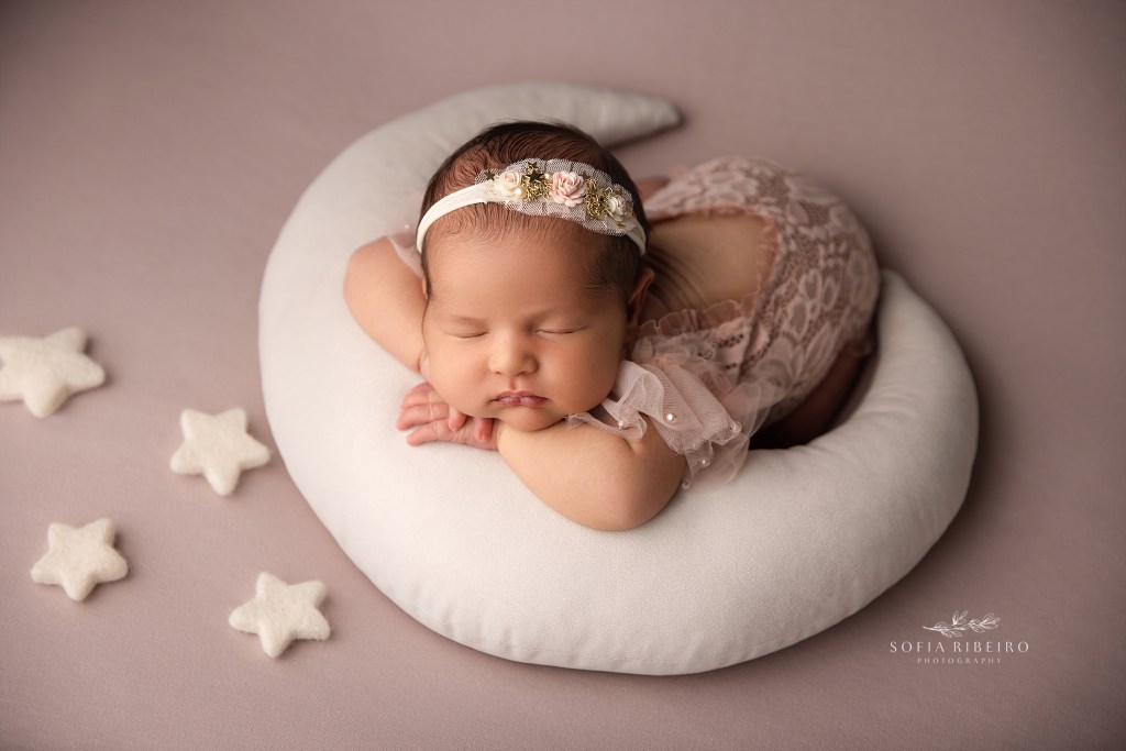 a newborn photographer expertly poses a baby girl on a moon prop during a session in maplewood nj