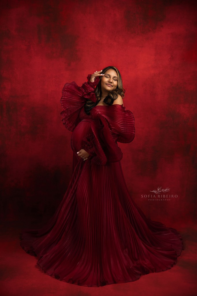 north brunswick nj maternity photographer poses a mom in a pleated red gown for a pregnancy portrait