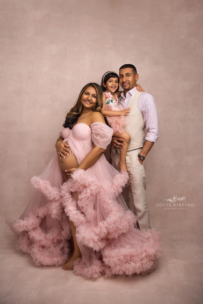 a family of three, soon to be four pose together for a family portrait with mom's baby bump in a north brunswick nj maternity photo studio