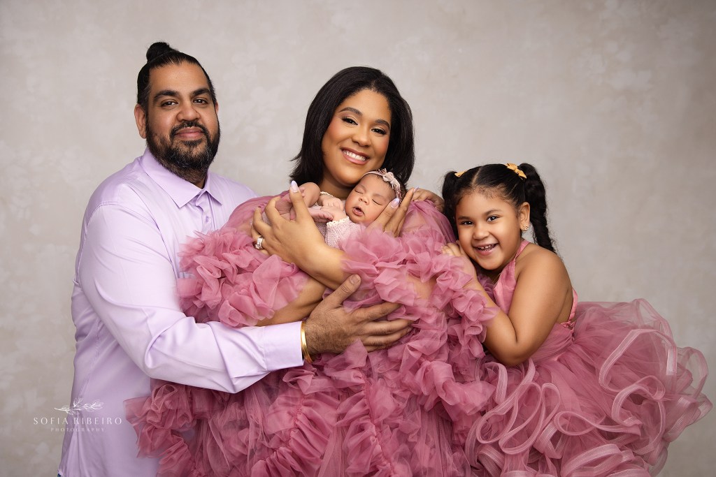 a beaming family of four captured during a newborn photo session in nj