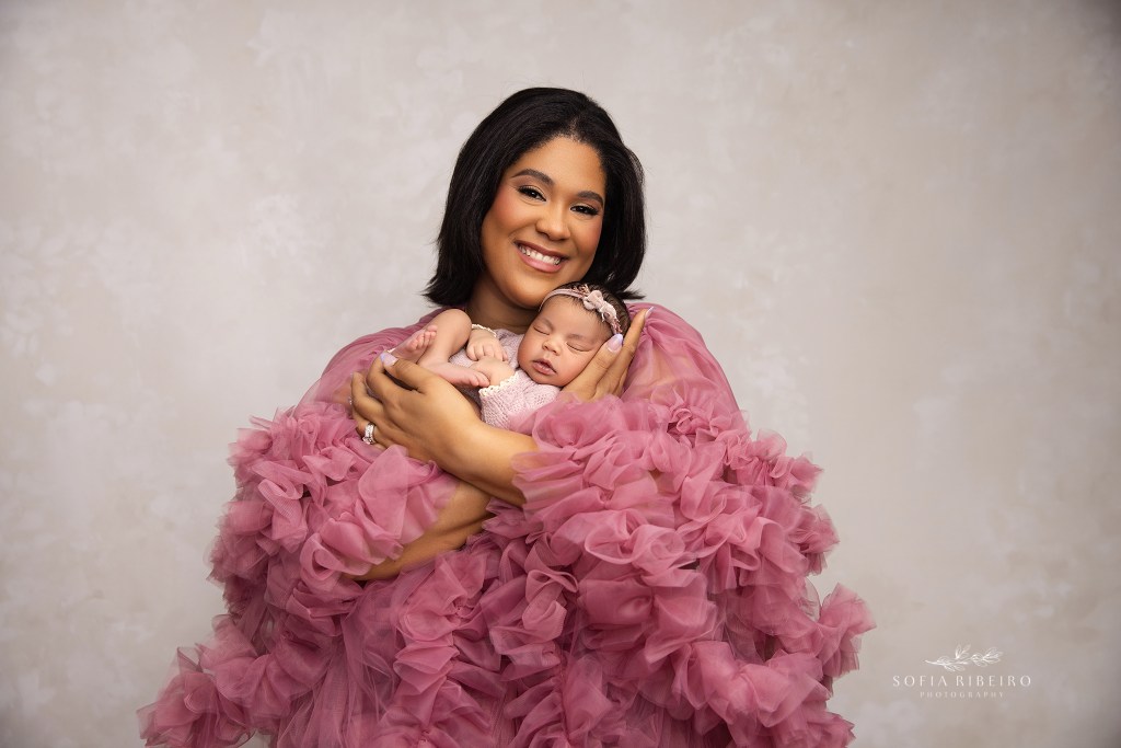 mom beams proudly to camera with her new baby daughter in hand