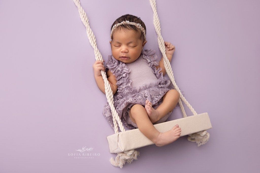 a faux swing prop carries baby girl in purple for a sleepy swing shot in sussex nj