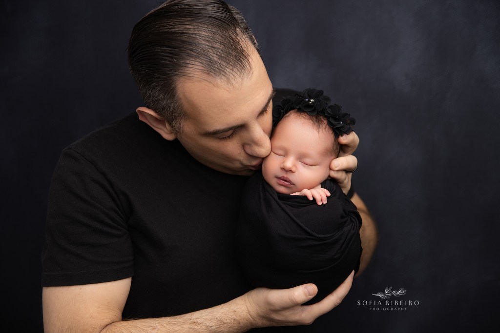 dad shares a sweet kiss with his newborn baby girl for a portrait