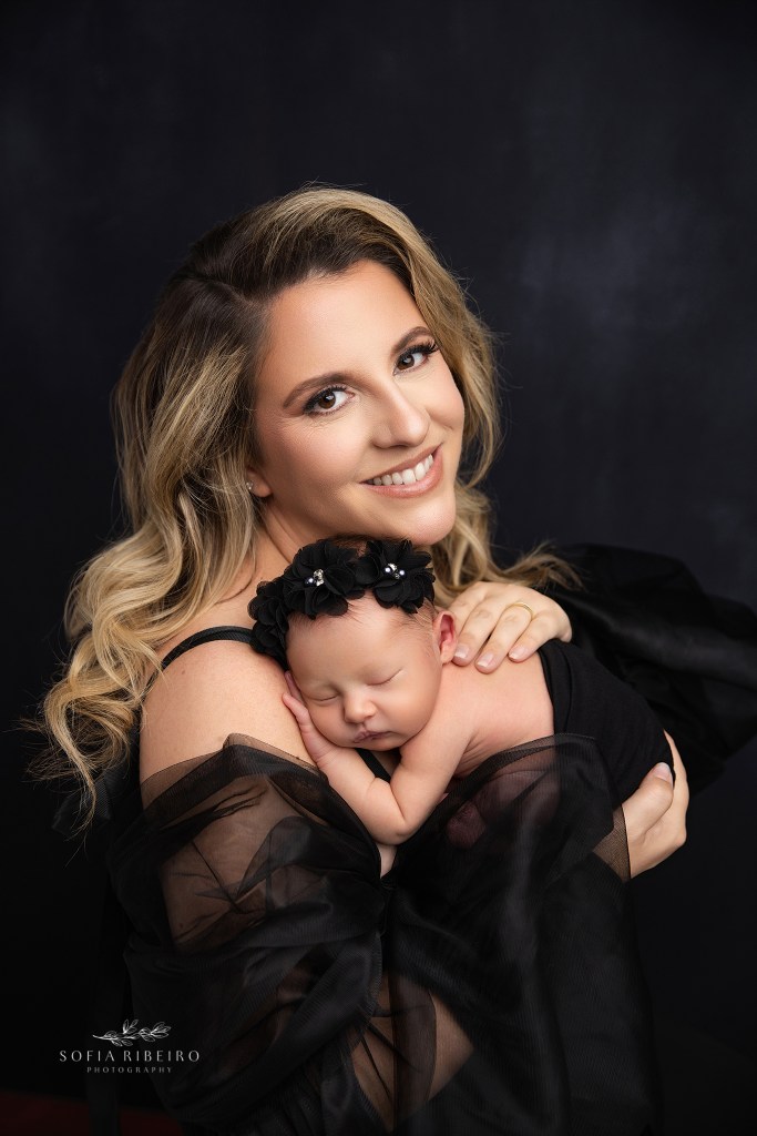 mom looks to camera, beaming with pride for newborn photos with hew baby girl in nj