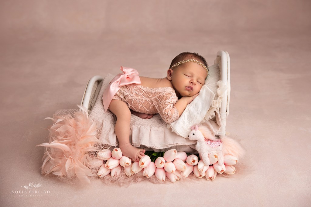 a holmdel nj newborn photographer poses baby girl on a bed prop surrounded by flowers and some sentimental pieces