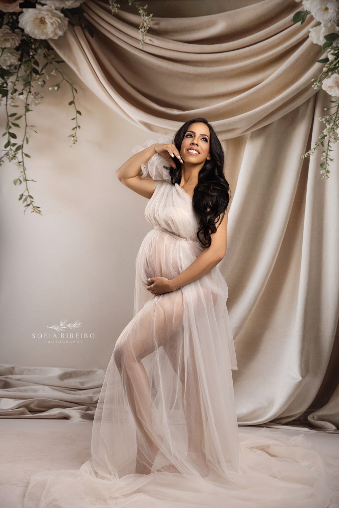 nyc maternity photographer captures mom glowing in her pregnancy against a draped cream and neutral backdrop