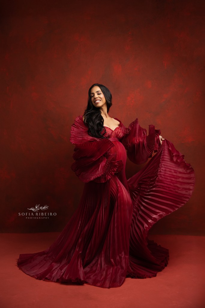 maternity in motion - a flowing pleated white dress showcases mom's baby bump in a portrait studio in new york