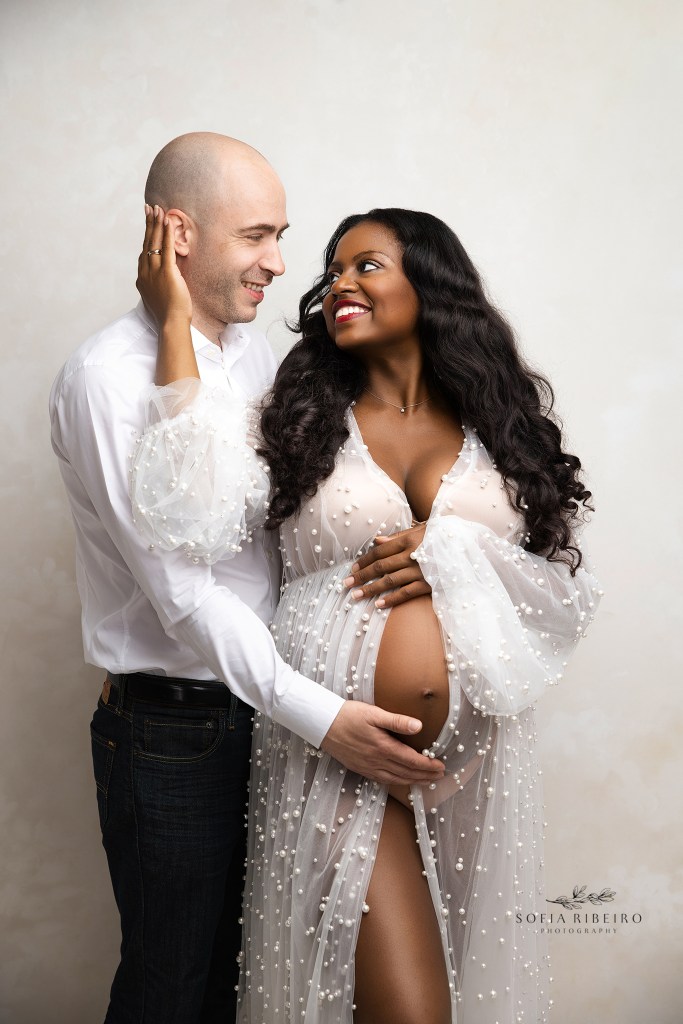 mom and dad share a sweet moment together while cradling the baby bump during a portrait session