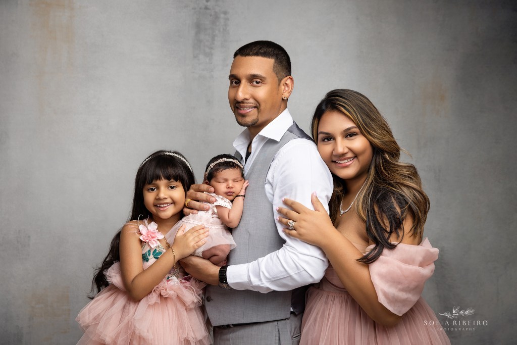 a beaming family of four welcomes their new baby girl in a nj newborn portrait studio