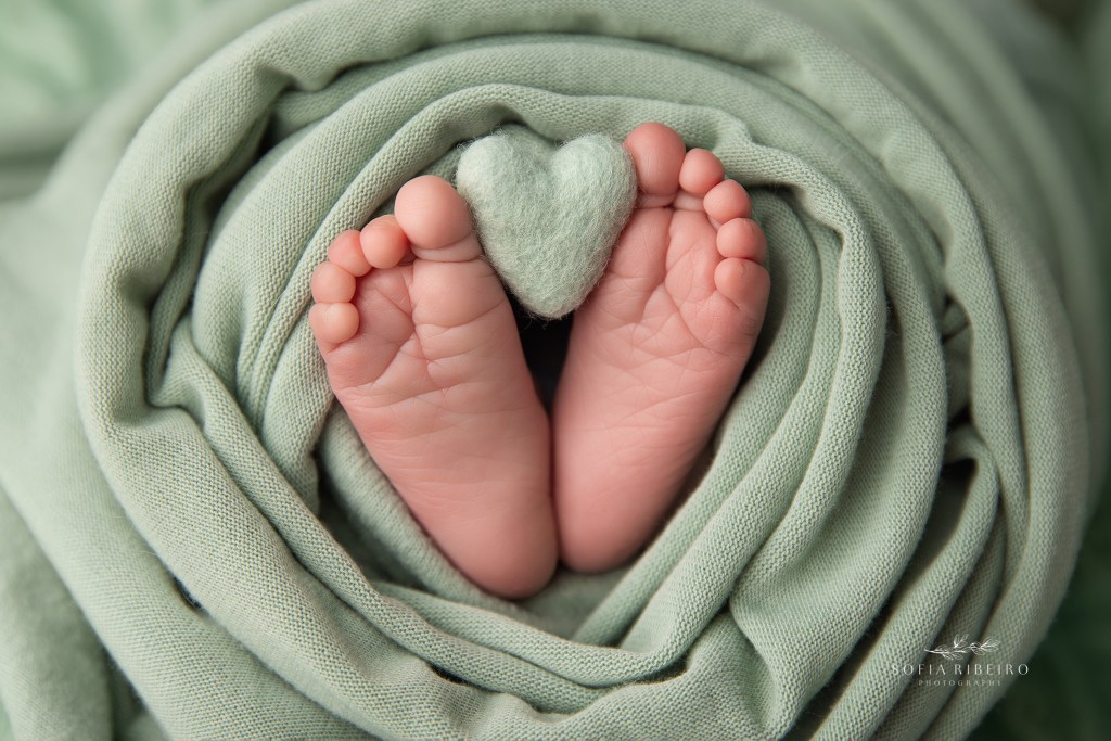 sweet details of baby's feet holding a heart prop