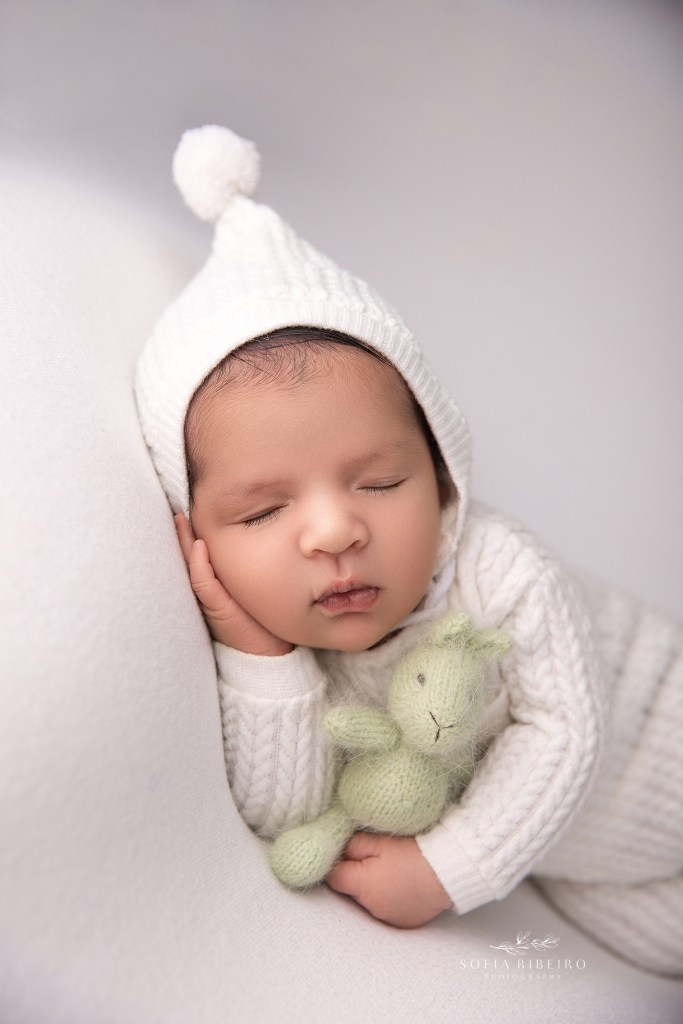 Delicate newborn portraits on white blankets with soft, natural textures, holding a stuffy