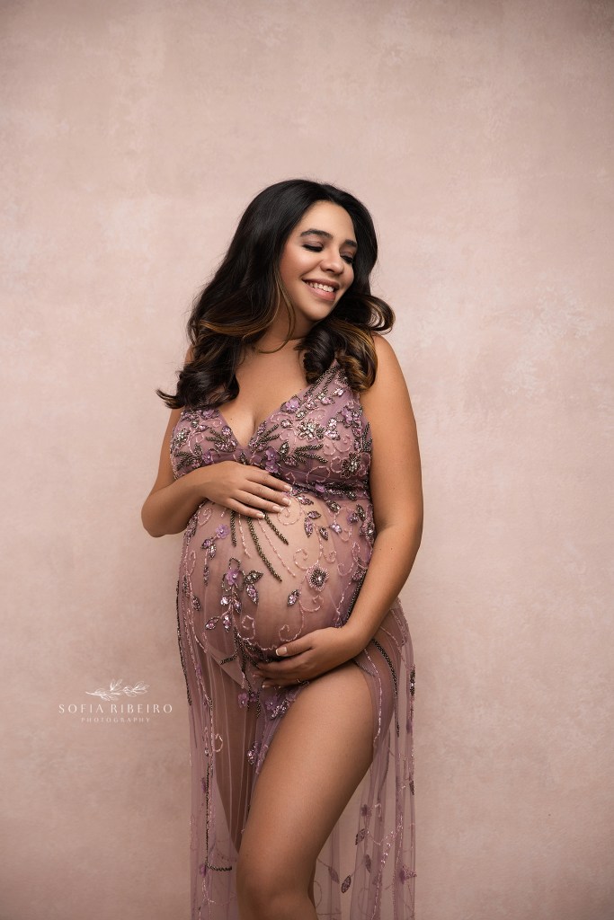 hillside nj maternity photographer poses mom cradling her baby bump in a sheer embellished pink gown
