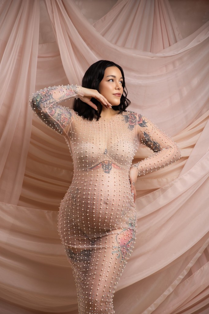 a new jersey maternity photographer captures a tattooed mom in a sheer pearl outfit against a draped backdrop