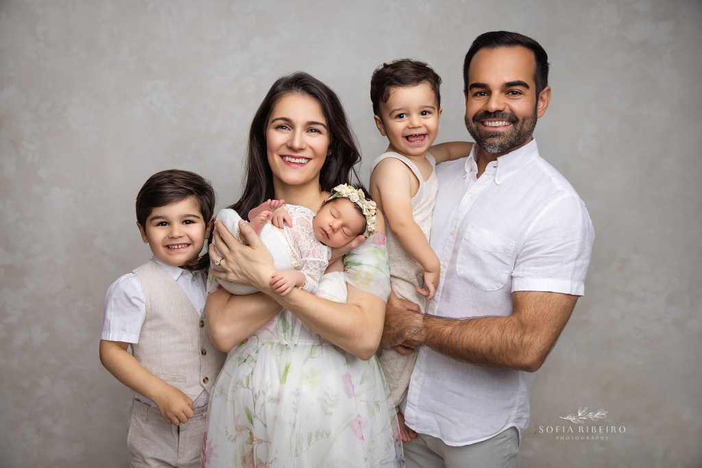 Complete family portrait in neutral tones, showcasing unique personalities and joyful connection, in a nj newborn photo studio