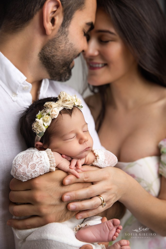 Close-up of newborn baby girl’s delicate features in her parents arms