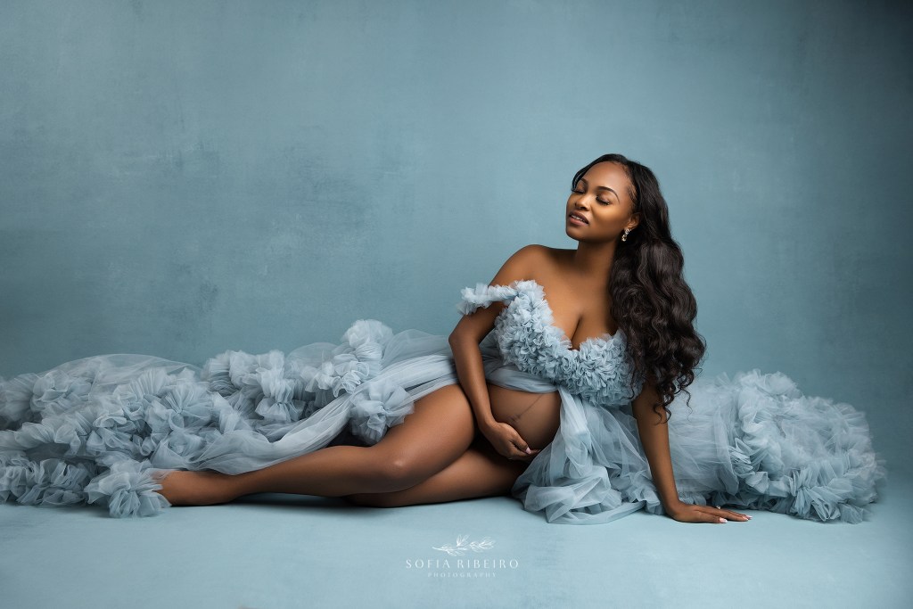 an elegant portrait of mom to be cradling her baby bump in a blue gown