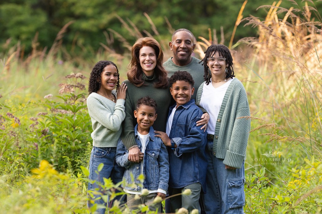 mom and dad pose with their 4 kiddos for a sweet family photo in some tall grasses in cranford nj