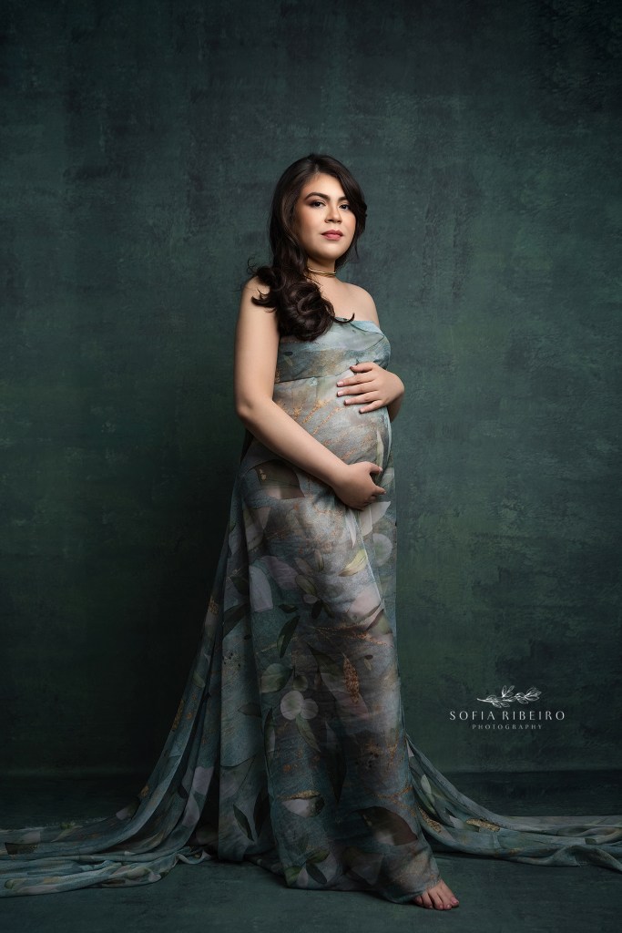 mom is a picture of classic elegance against green hues and draped fabric hugging her baby bump