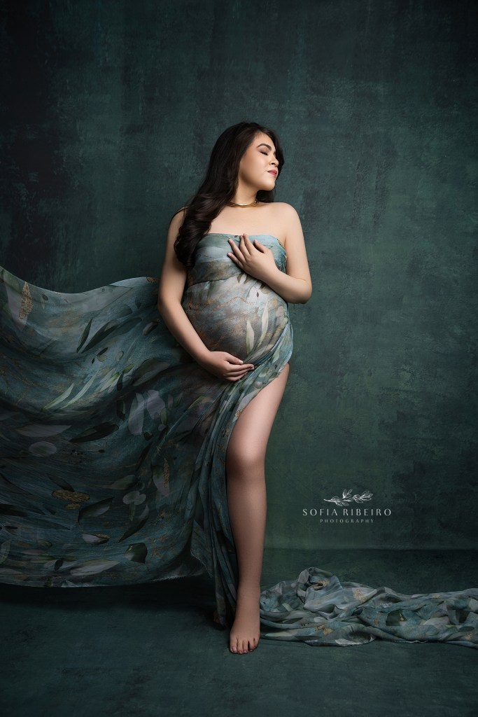 mom is a picture of classic elegance against green hues and draped fabric hugging her baby bump