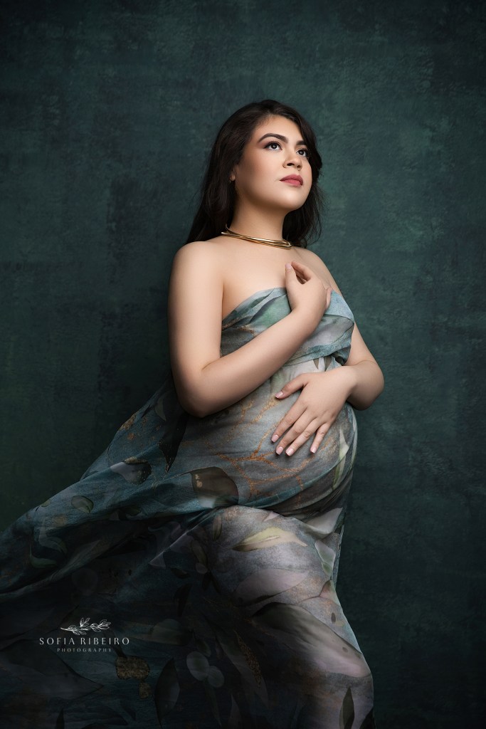 a closeup of a gorgeous mom to be cradling her baby bump in maternal glow