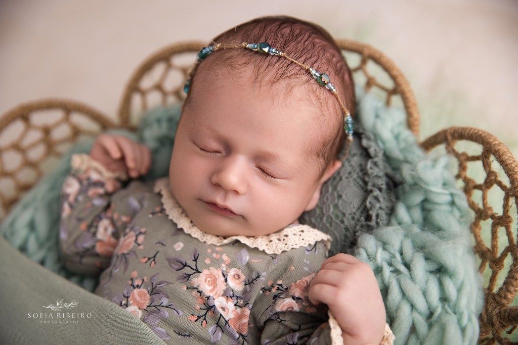 a baby girl sleeps sweetly in soft green hues during a newborn photo session in nj
