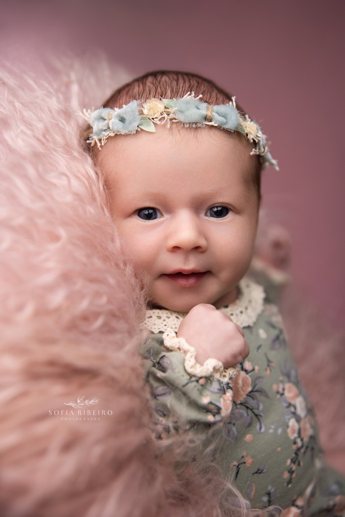 a wide eye'd baby girl focuses on the camera during a newborn session