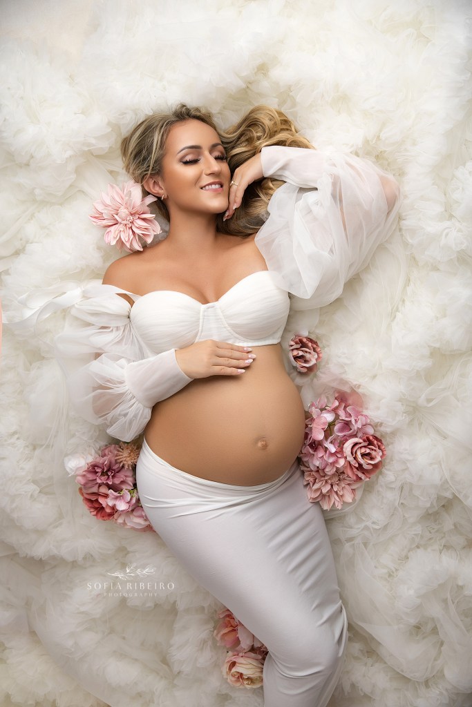 and expectant mom is posed in a two piece white outfit for maternity portraits in a nj photo studio