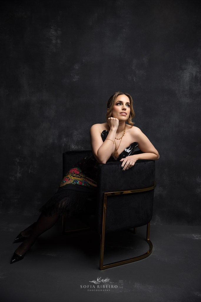 beautiful 40 year old is perched in a chair in a black bustier for 40th birthday photos