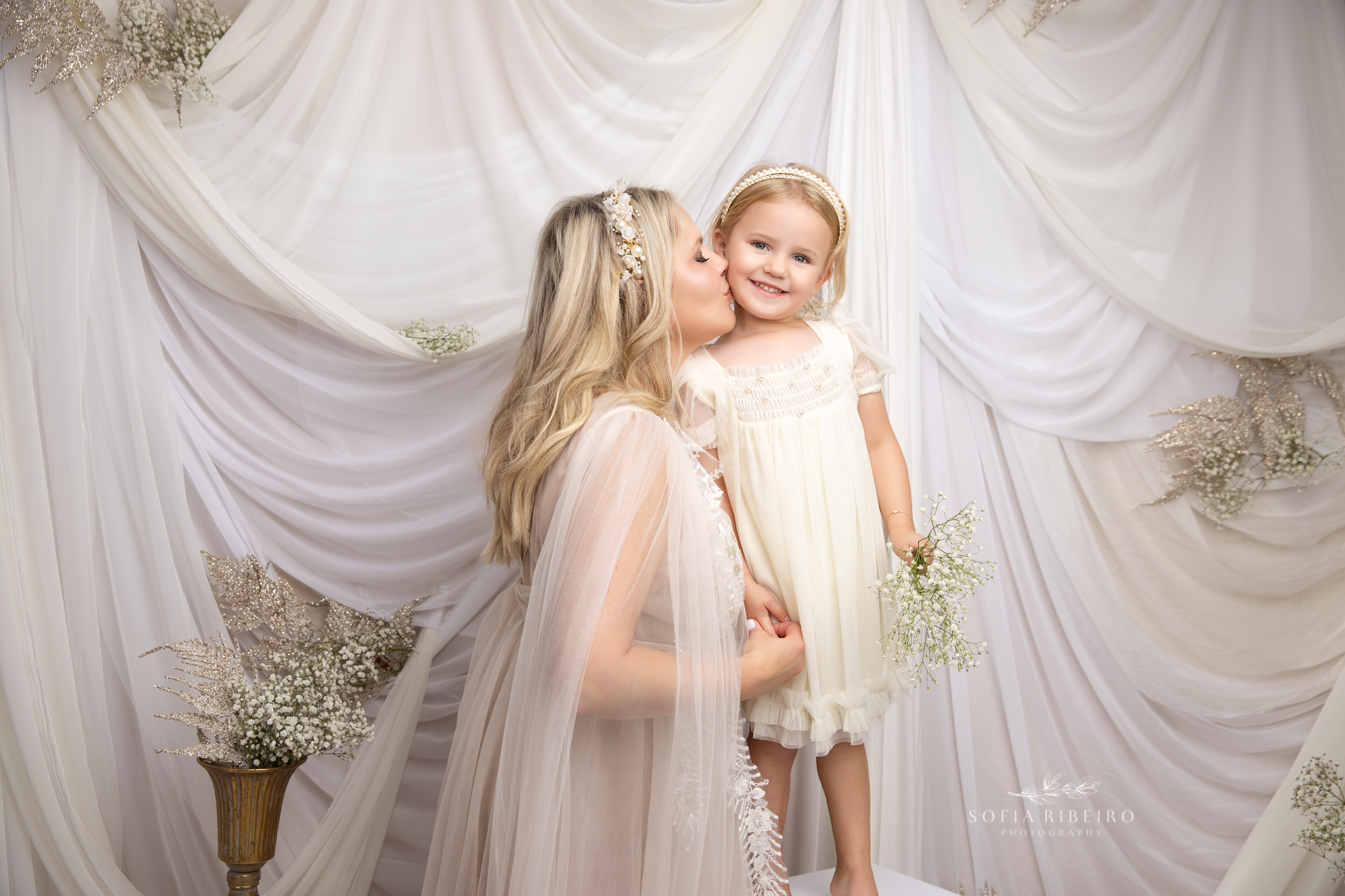 mom gives her sweet girl a soft kiss, with all smiles for a mommy and me photoshoot in a nj studio