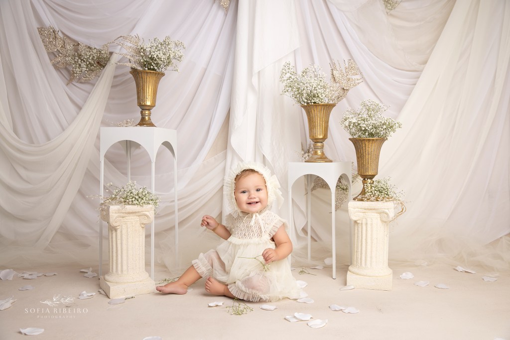 a precious baby in tulle dress and matching bonnett giggles to camera for a mother daughter photo session