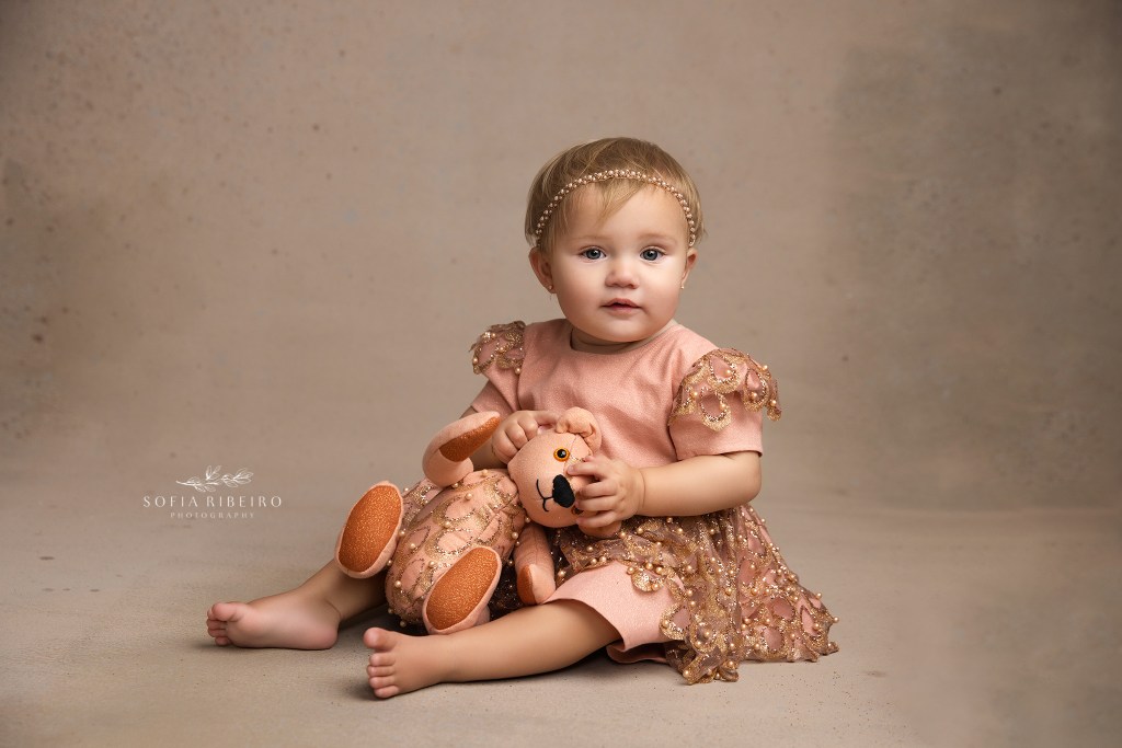 a little baby girl cuddles her custom teddy bear made to match her dress