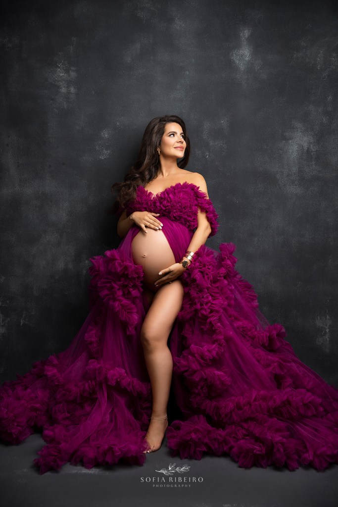 expectant mom to be is gorgeous in a hot pink tulle gown against a black backdrop shot by a south jersey maternity photographer
