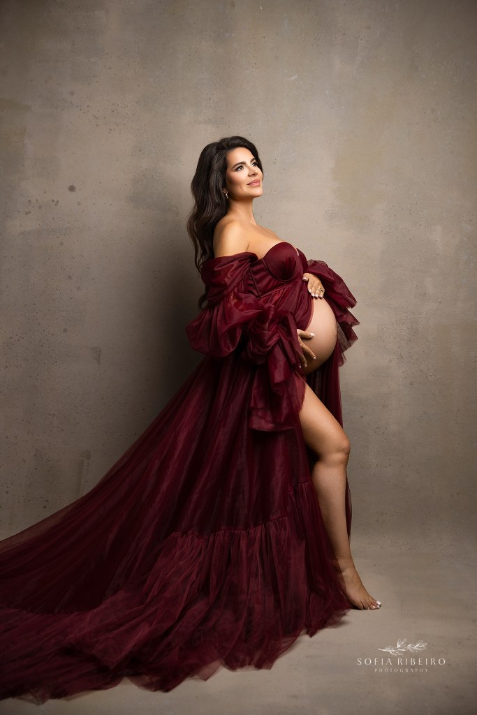 mom is a picture of elegance in a deep burgundy tulle gown showcasing her baby bump