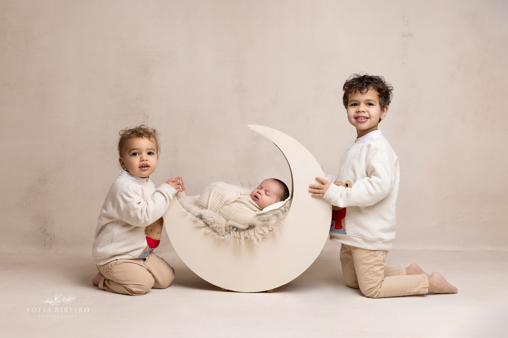 two older brothers cradled a moon prop with their new baby brother inside